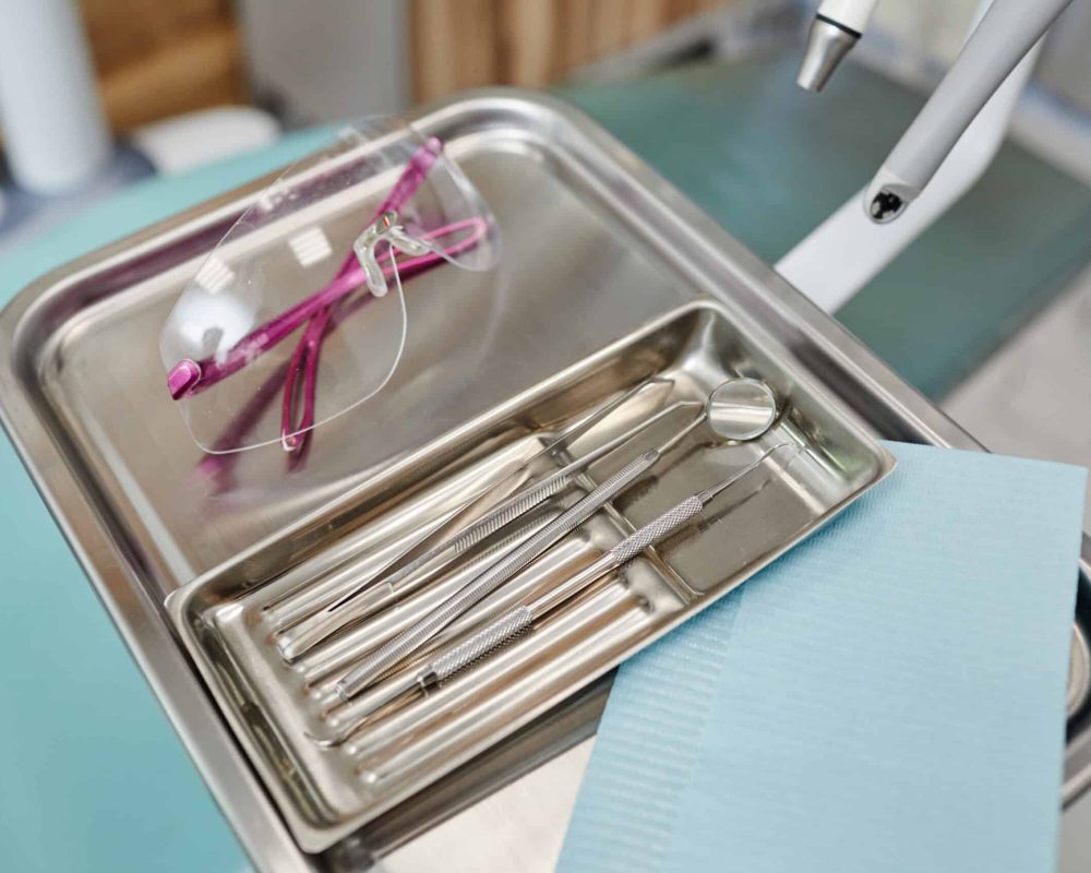 Background image of sterile metal tools on tray in modern dental clinic, copy space