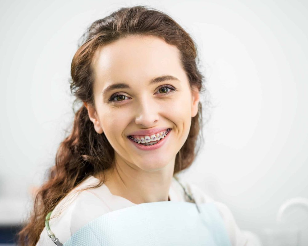 happy woman with braces on teeth smiling in dental clinic